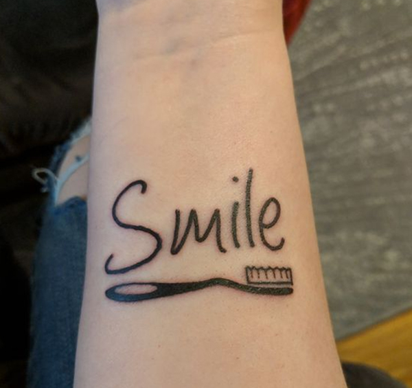 Hình xăm chữ smile kết hợp bàn chải đánh răng độc đáo trên cánh tay